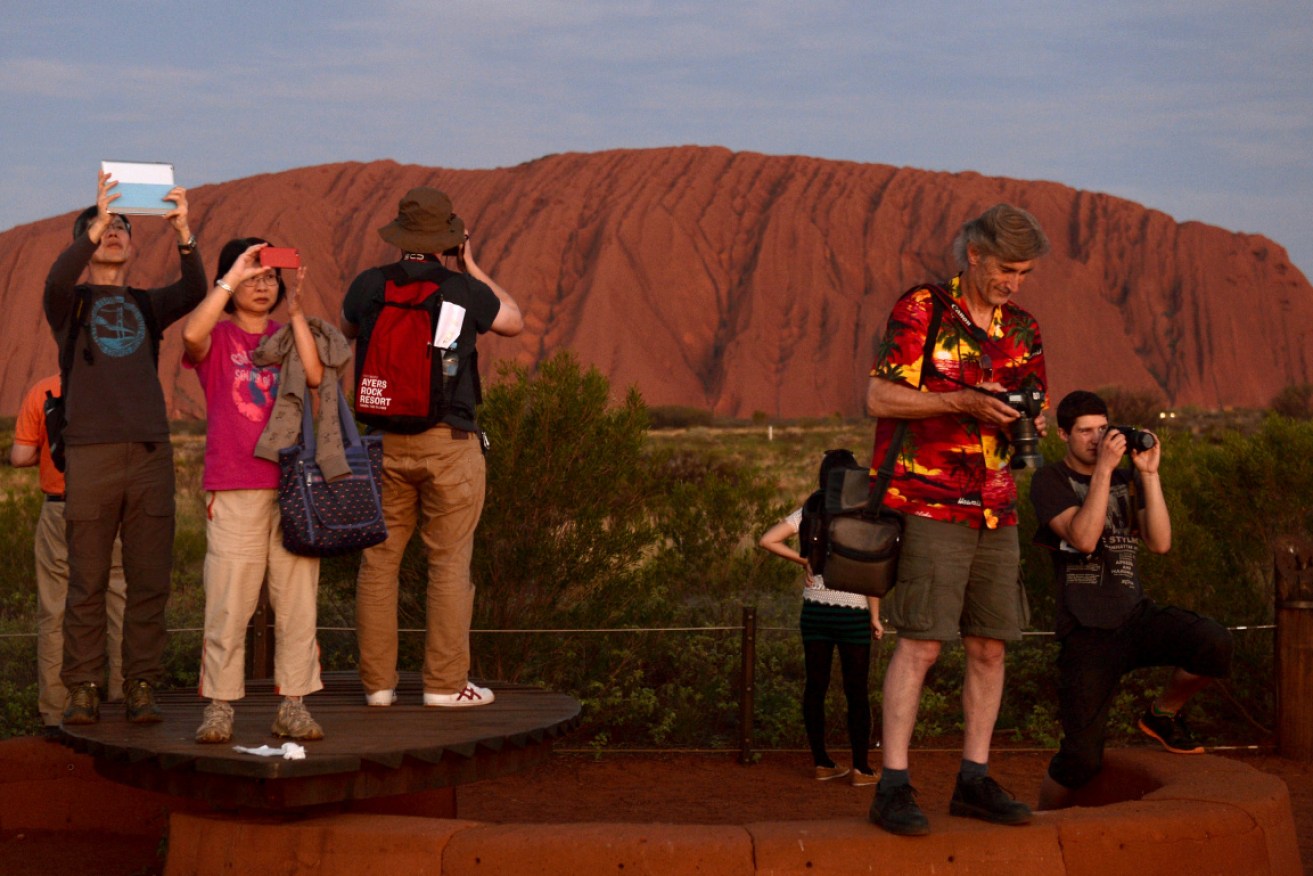 Tourists photograph the sunset at Uluru (Ayer's Rock) in the Northern Territory. 