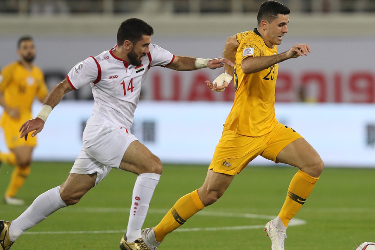 Match winner Tom Rogic is tracked by Syria’s Tamer Hag Mohamad at Al Ain, UAE. 
