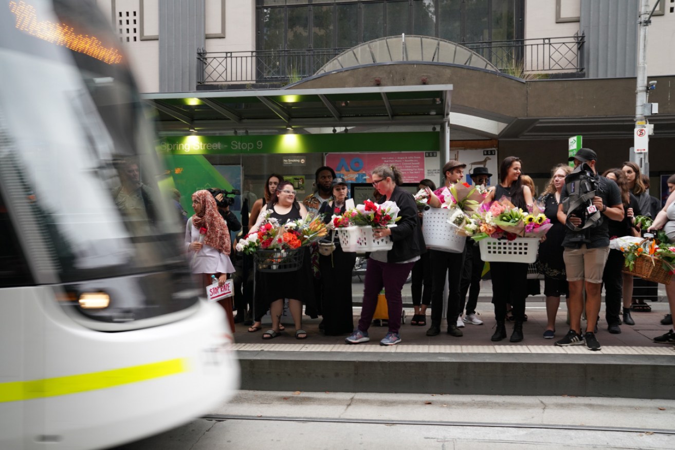 People prepare to ride the 86 tram with flowers for Aiia Maasarwe's vigil at parliament house.