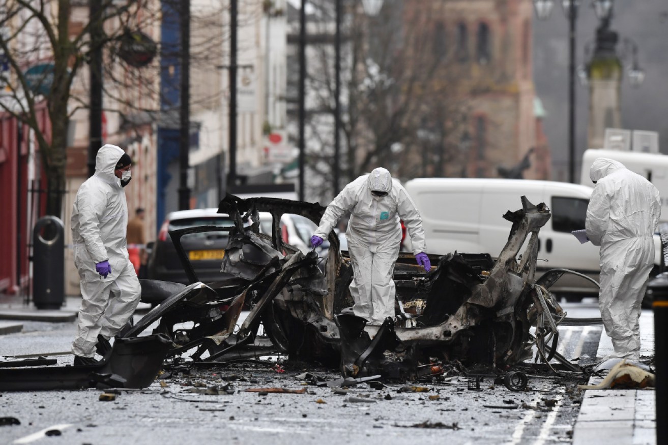 Police inspect the remains of the car blown up in Londonderry on the weekend.