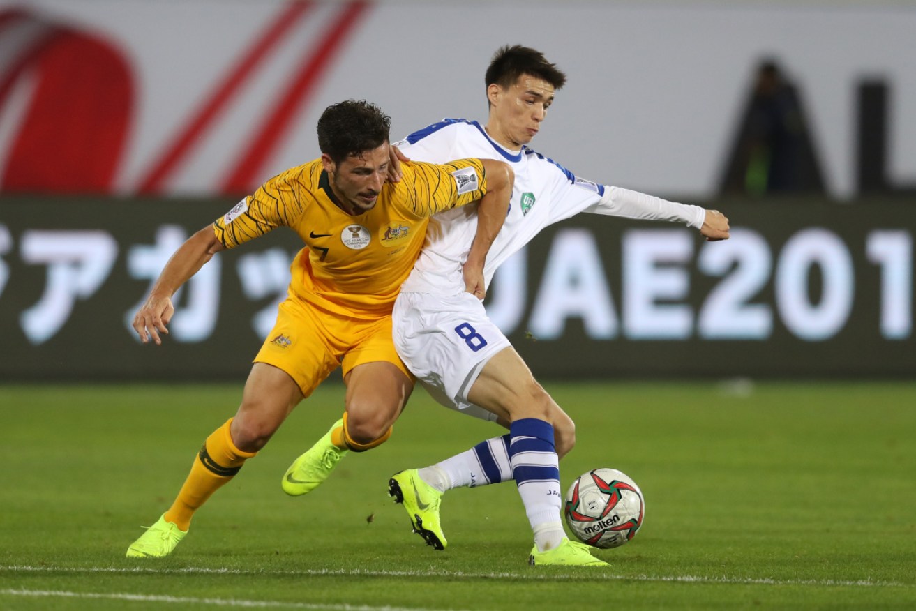 Mathew Leckie battles for possession with Ikromjon Alibaev during the AFC Asian Cup match.