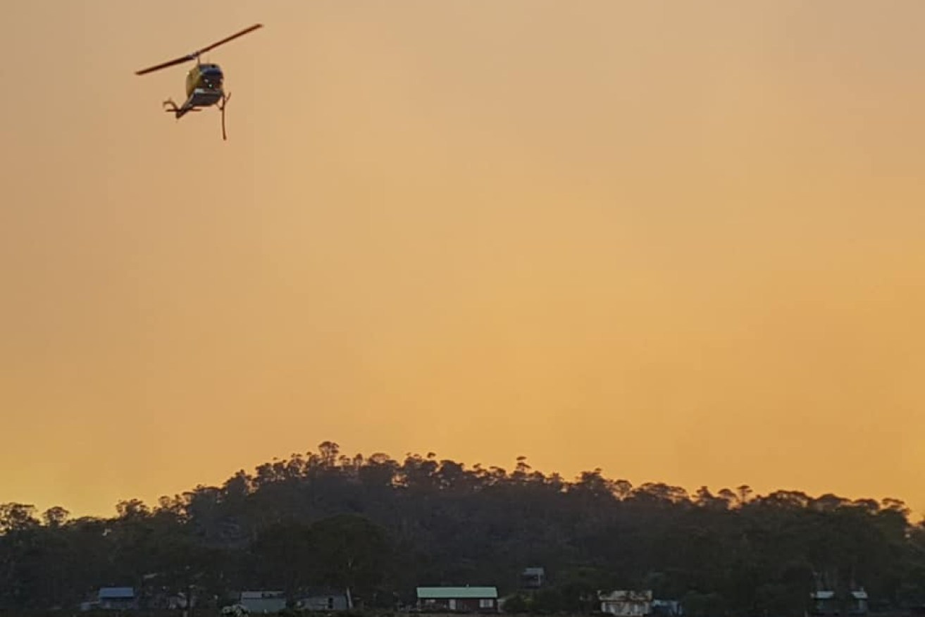 A helicopter battles the blaze at Meina, in central Tasmania.