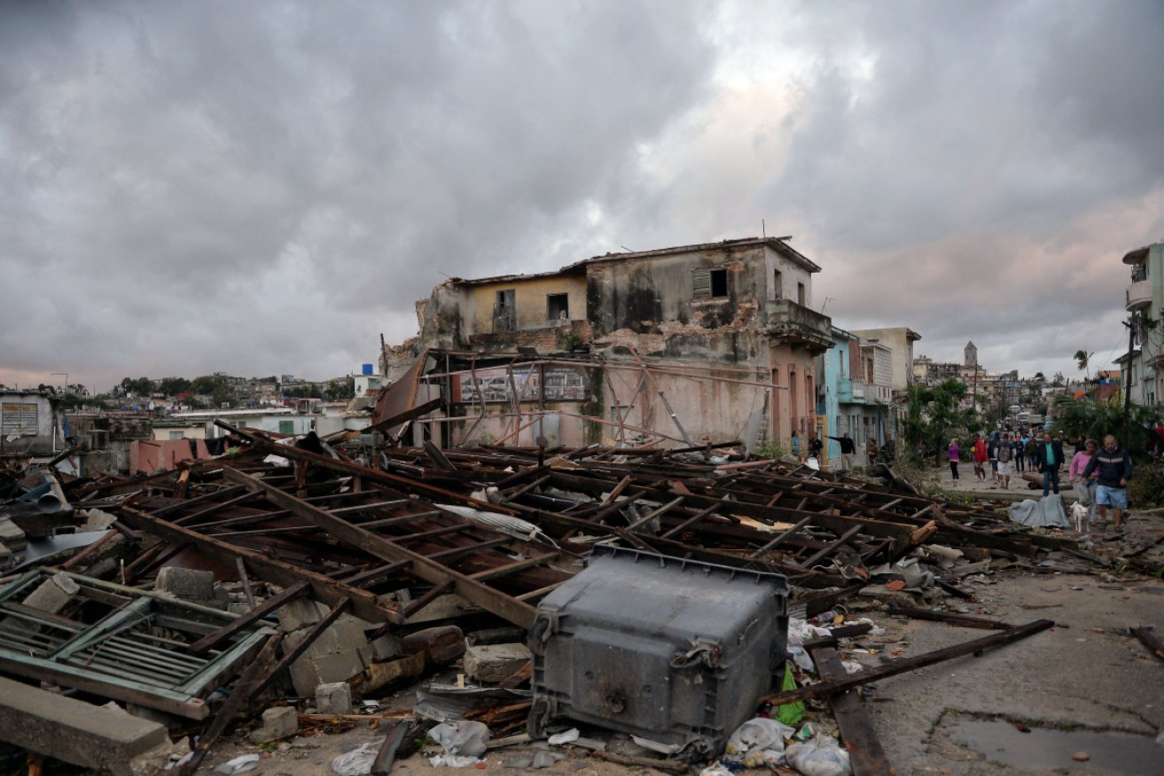 Residents walk amid the debris from their destroyed homes, after the passage of a tornado in Havana,