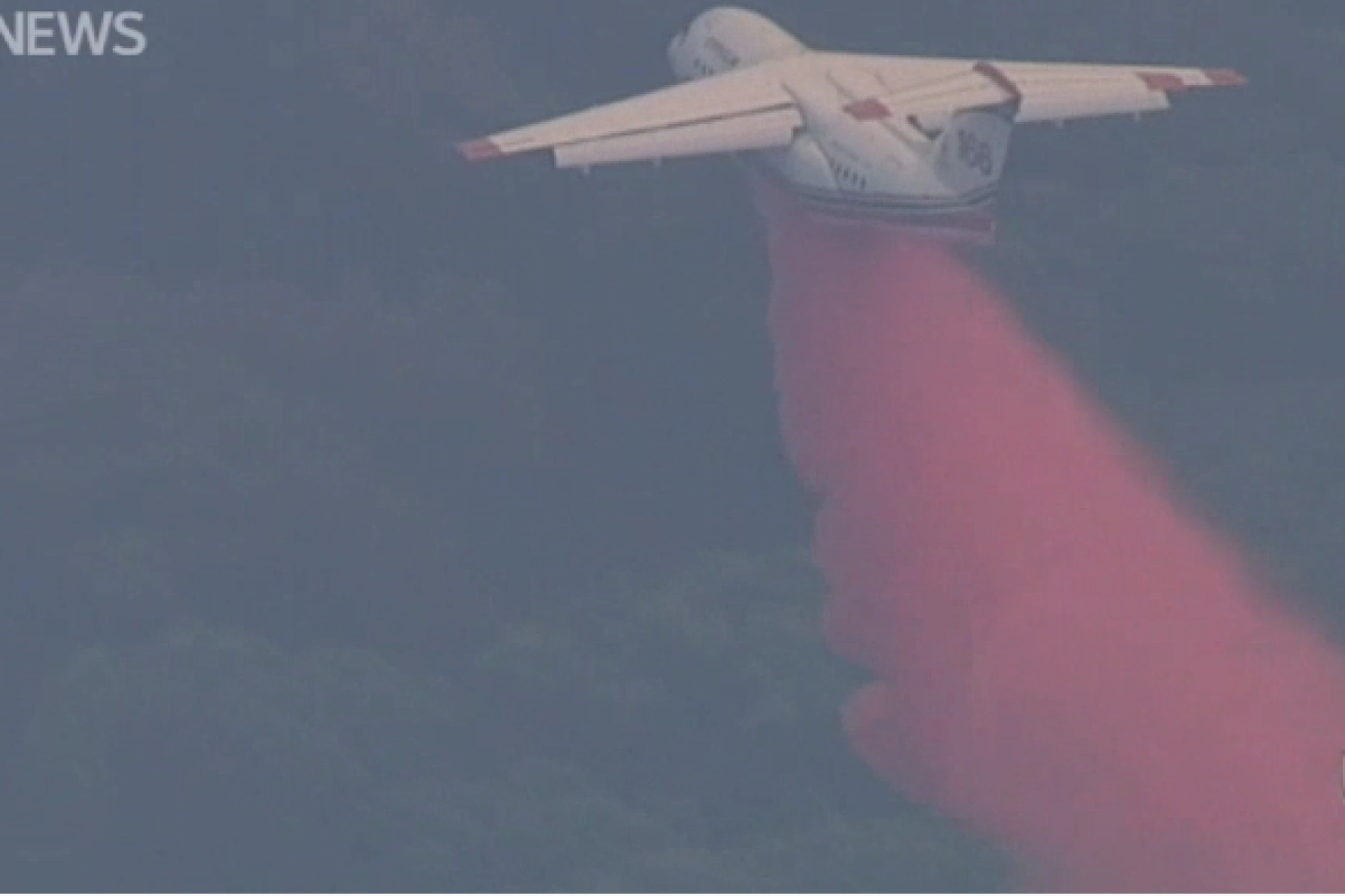 An airborne tanker disgorges i ts cargo of fire-retardant chemicals on the  Hepburn inferno.