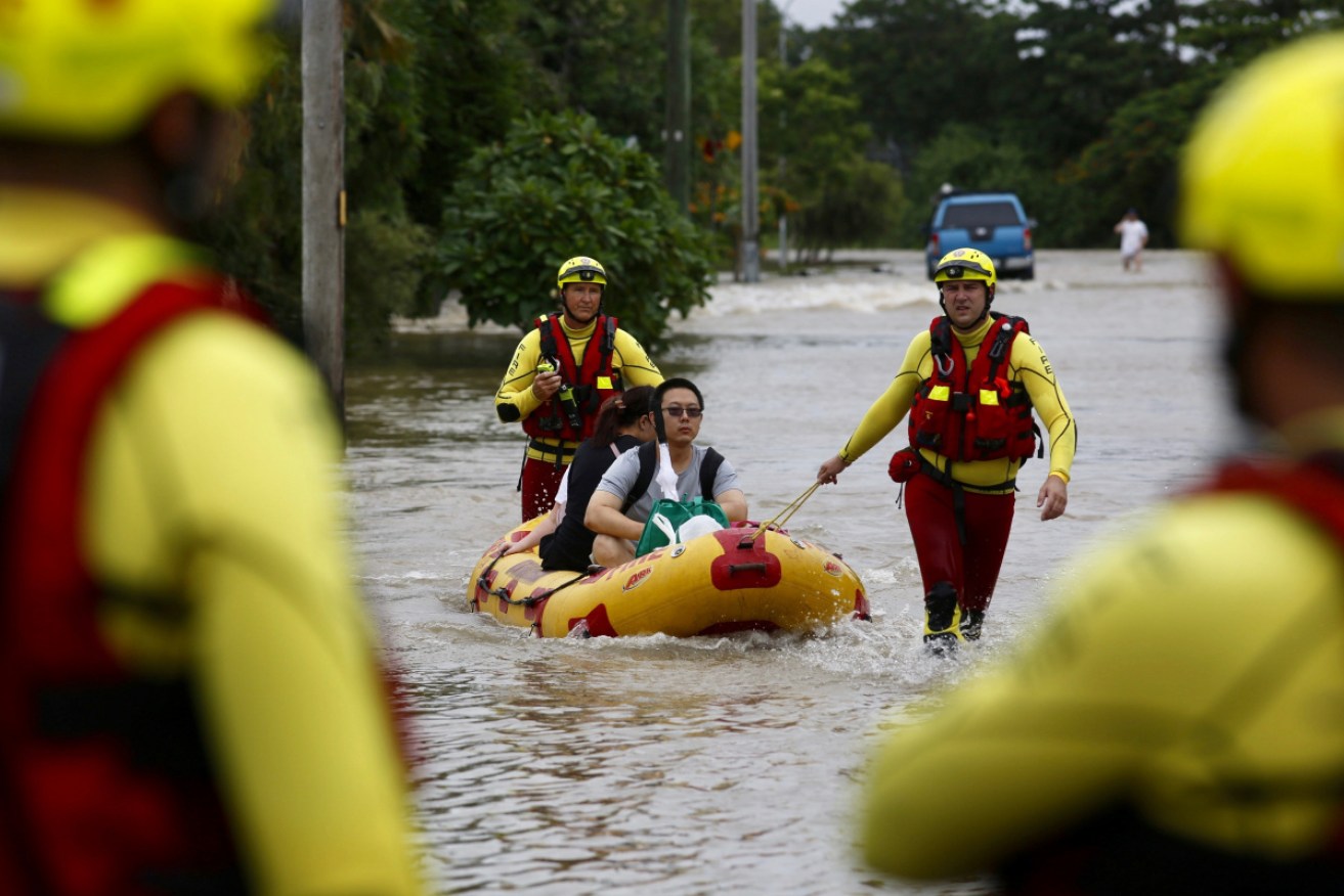 Queensland Fire and Emergency Services crew members rescue residents in flooded Hermit Park.