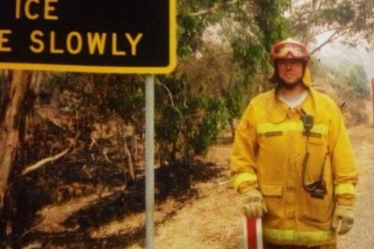 Brad Waterhouse (near a sign warning of ice on the roads) after the Black Saturday inferno. 