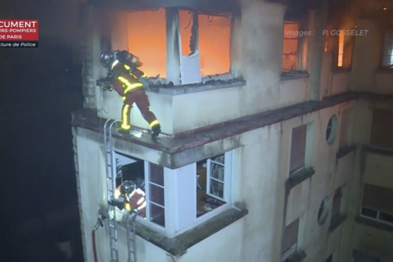 Firemen scale the top floors of an apartment building in Paris.  