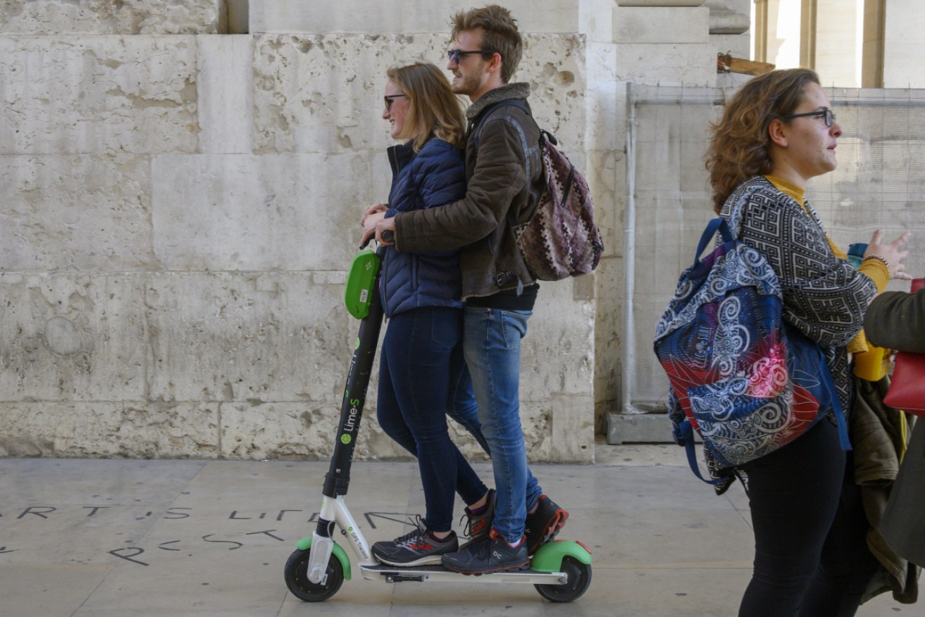 A couple ride a Lime scooter in Lisbon, Portugal. 
