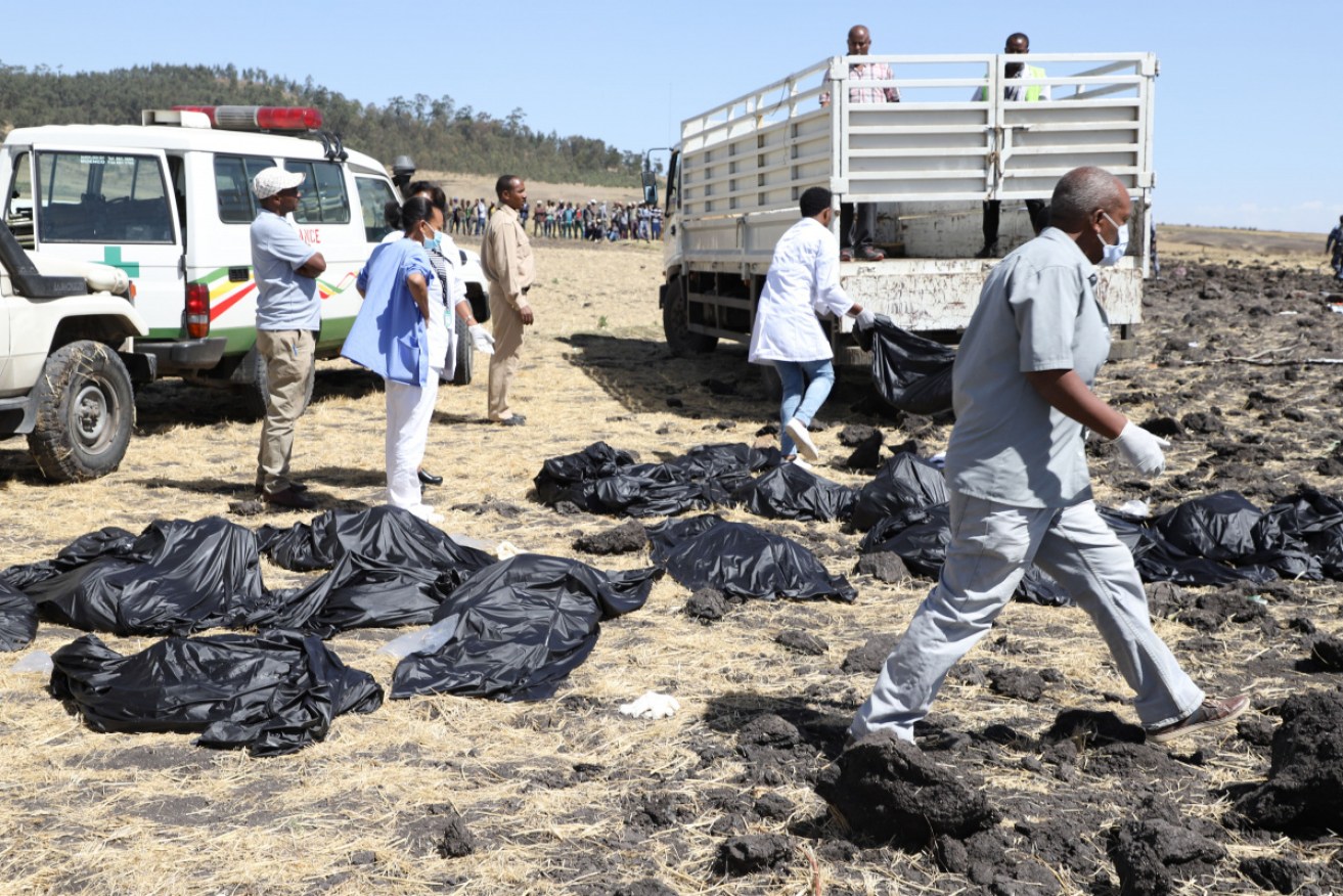 Rescue team walk past collected bodies in bags at the crash site of Ethiopia Airlines near Bishoftu.