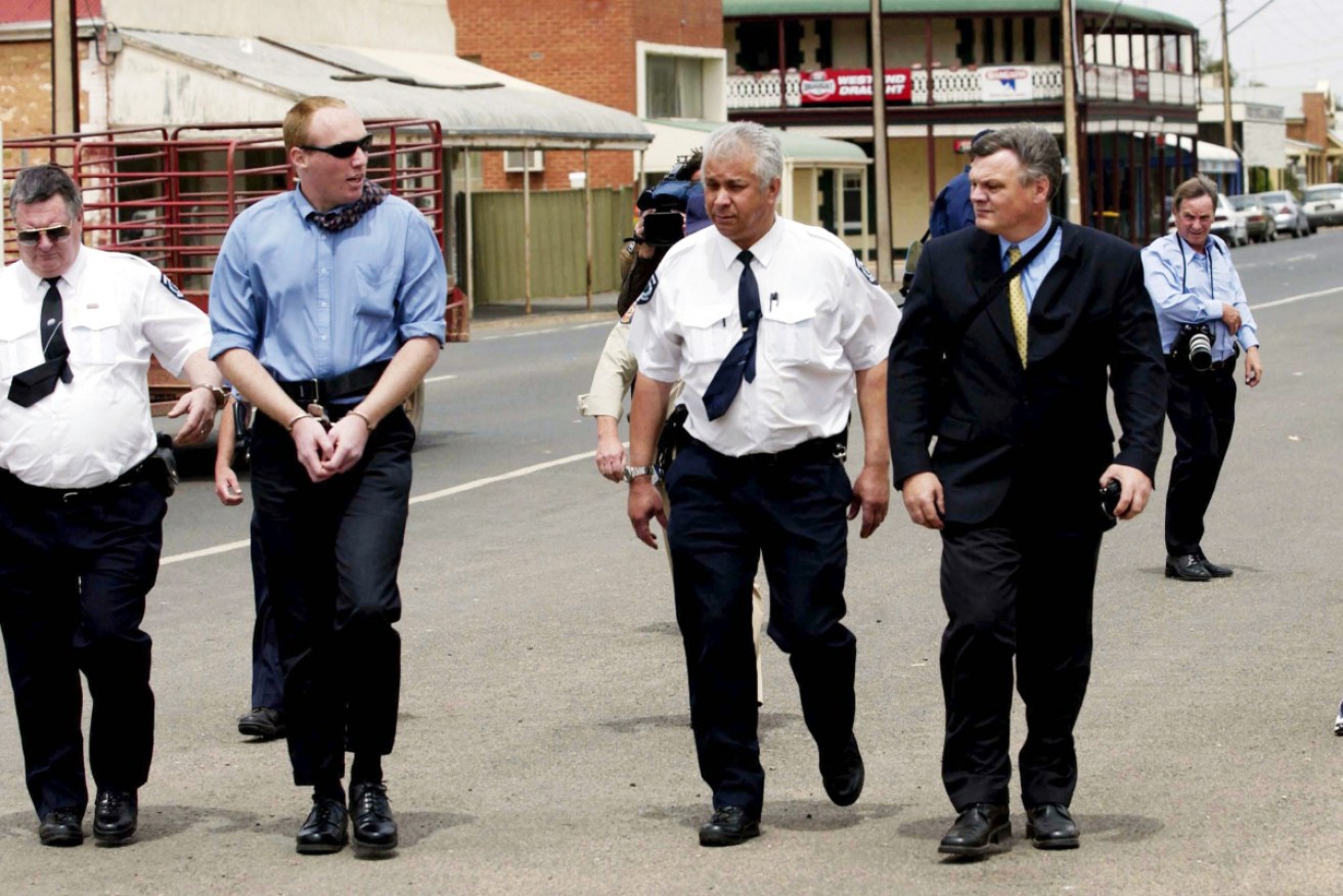 A handcuffed Robert Joe Wagner is escorted through Snowtown during his murder trial.