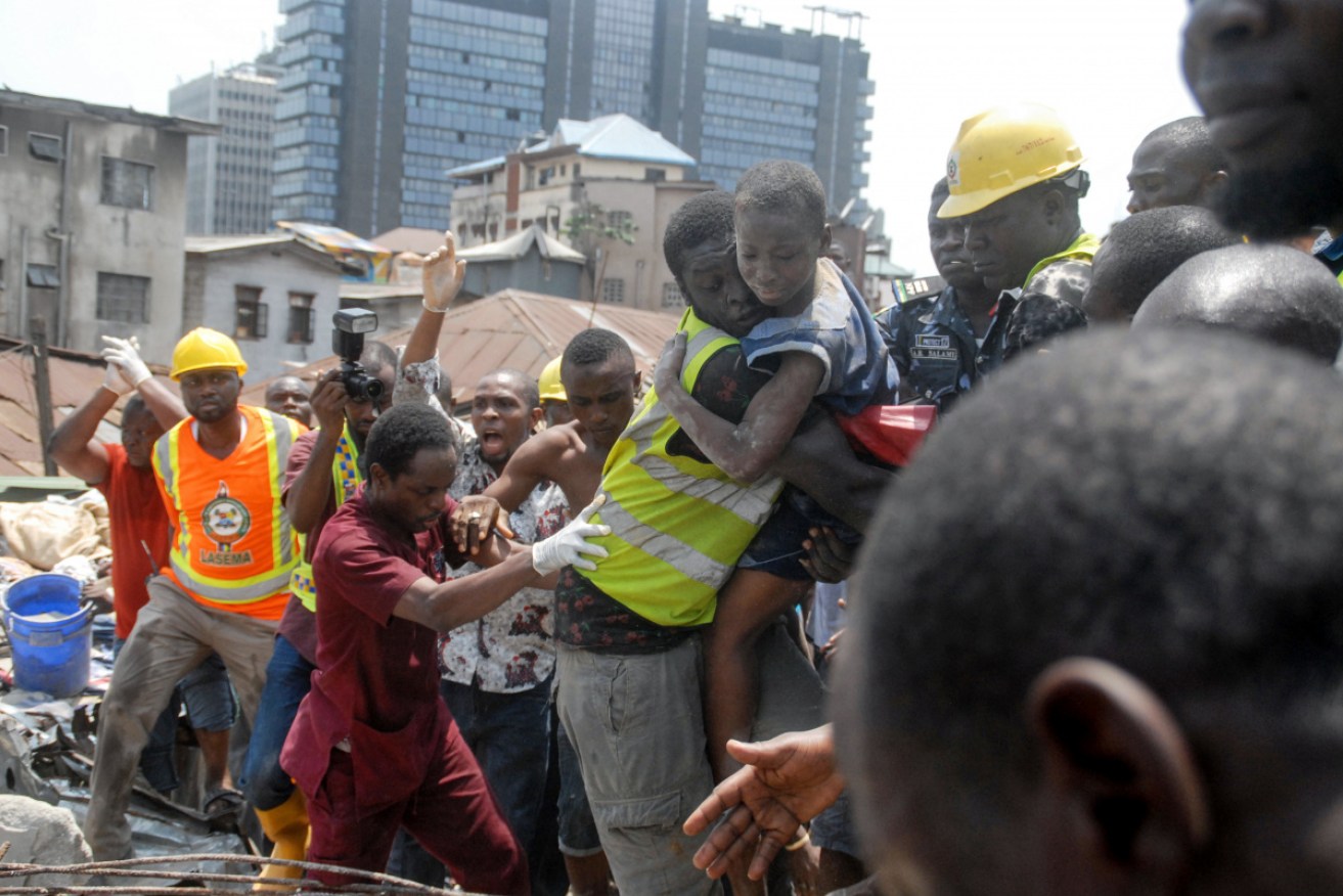Emergency personnel rescue a child at the site of a building which collapsed in Lagos.