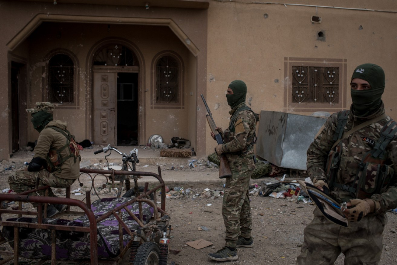 Syrian Democratic Firces fighters are seen in front of a building in the final ISIL encampment.