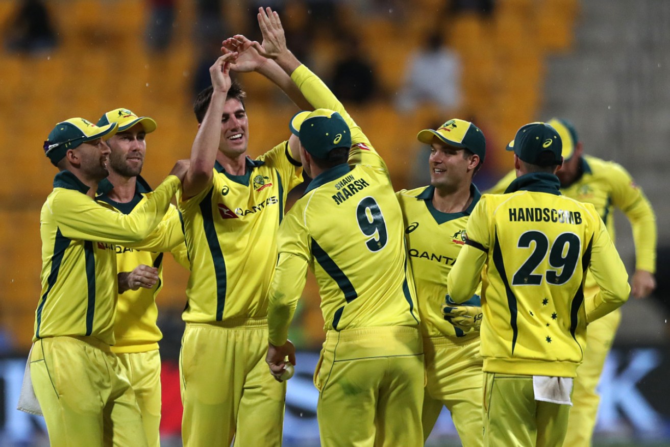 Australian cricketer Patrick Cummins (3rd-L) celebrates with his teammates the dismissal of Pakistani cricketer Haris Akmal.