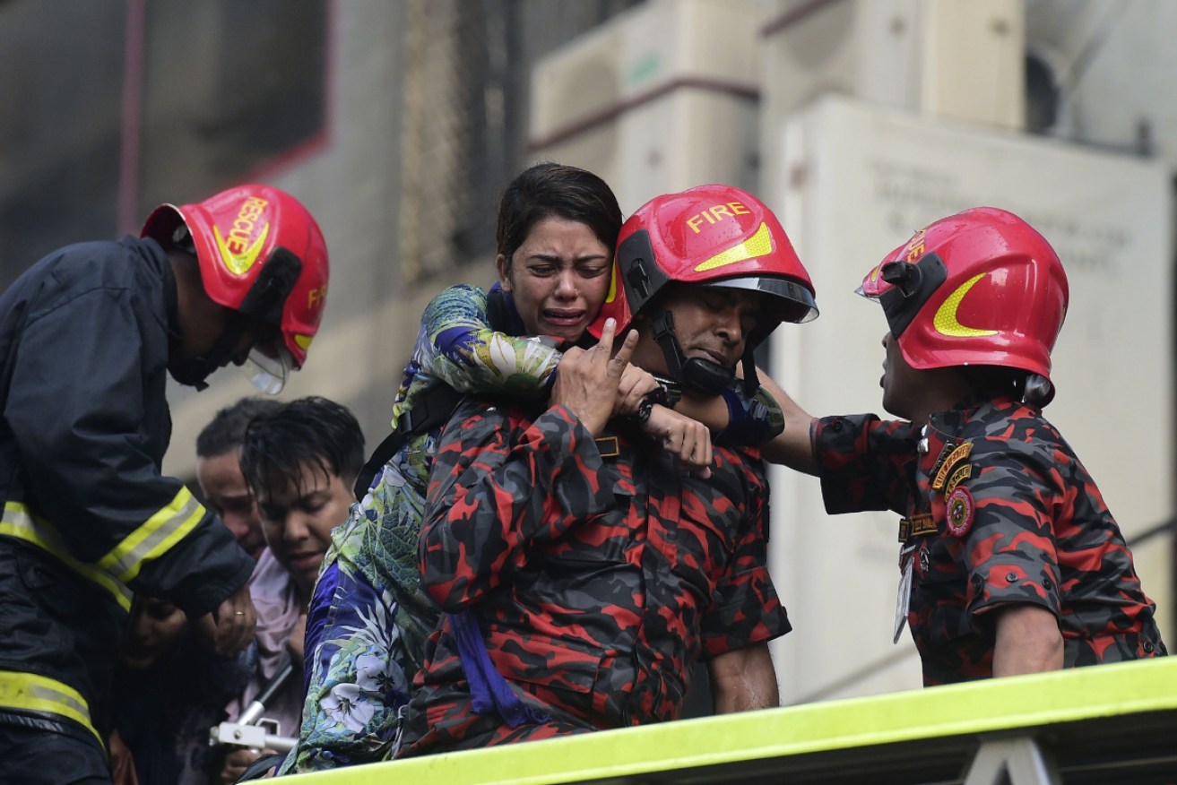 A Bangladeshi survivor reacts after being rescued by firefighters from a burning office building in Dhaka.