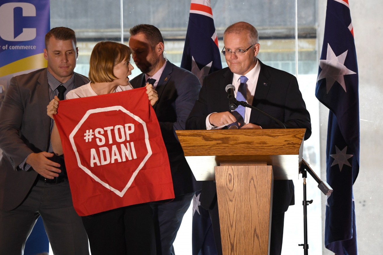 An anti-Adani protester storms the stage at the PM's address.