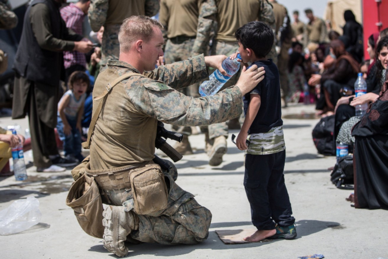 Troops have been helping families who are waiting for evacuation flights at Kabul airport.