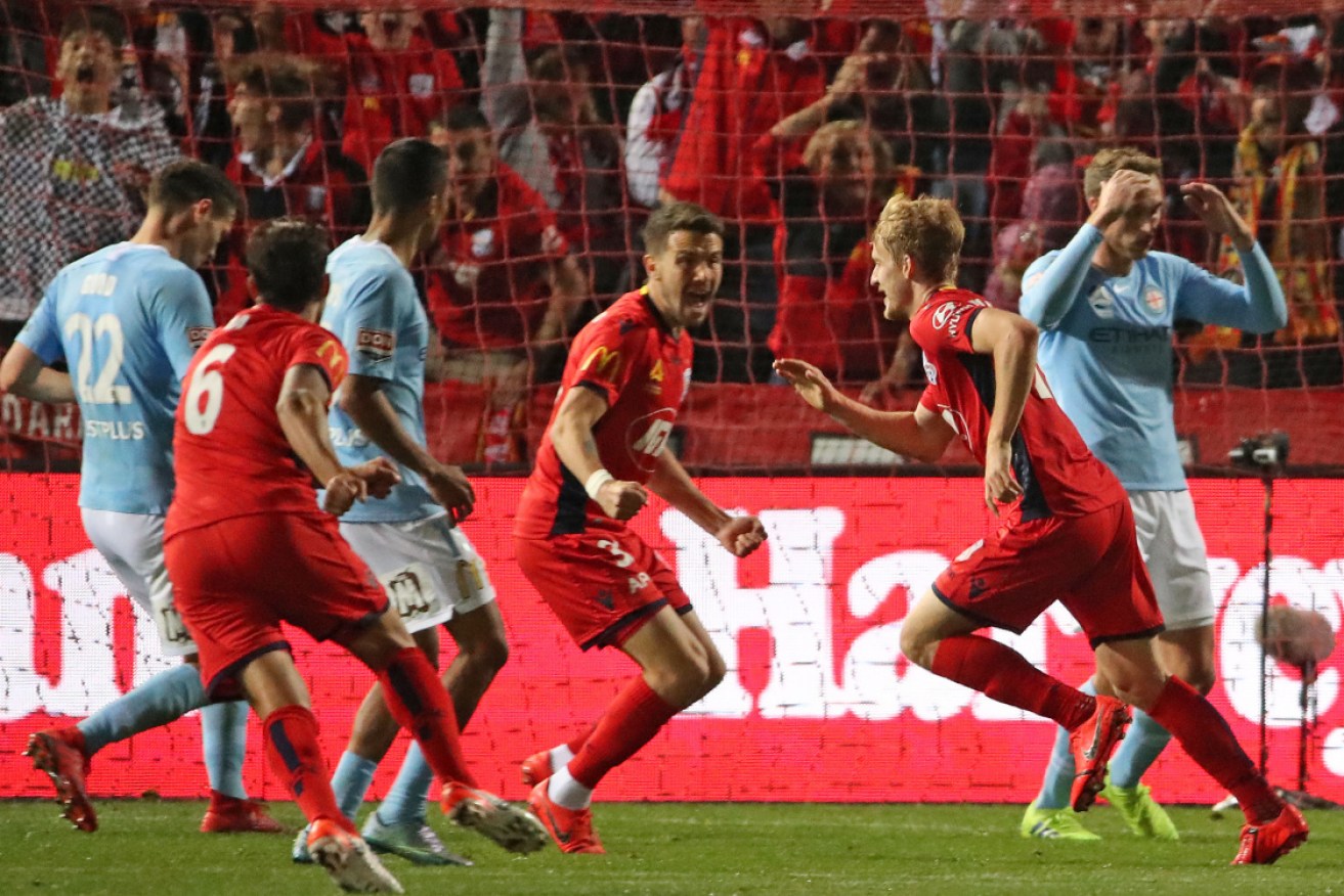 Adelaide United's Ben Halloran, right in Red, celebrates his late winner. 