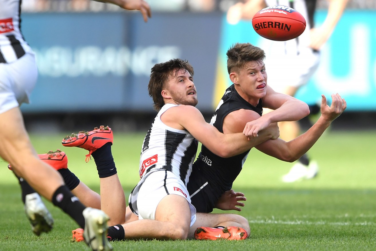 Carlton's Sam Walsh gets a handball away despite the attentions of Magpie Tom Phillips. 