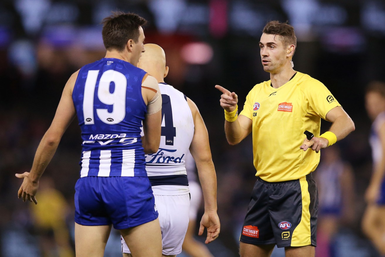 The umpire takes the name of Gary Ablett Jr as North's Robbie Tarrant remonstrates.