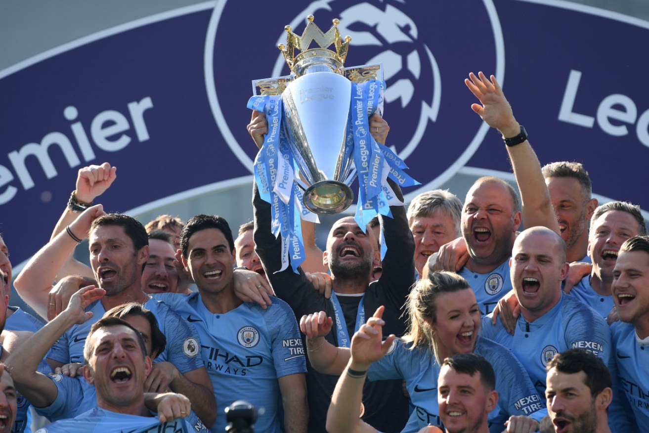 Manchester City manager Pep Guardiola holds the winner's trophy.
