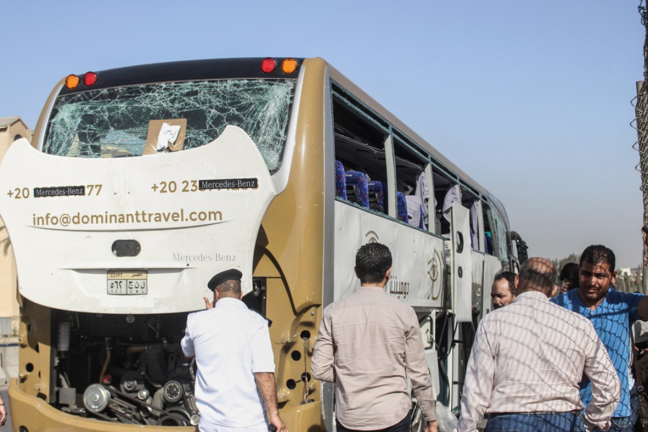 People and security personnel stand next to a damaged tourists' after a bomb explosion.