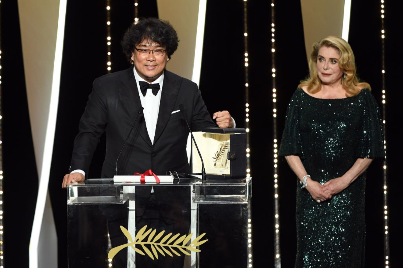 Director Bong Joon-Ho receives the Palme d'Or award for <i>Parasite</i> from Catherine Deneuve.
 