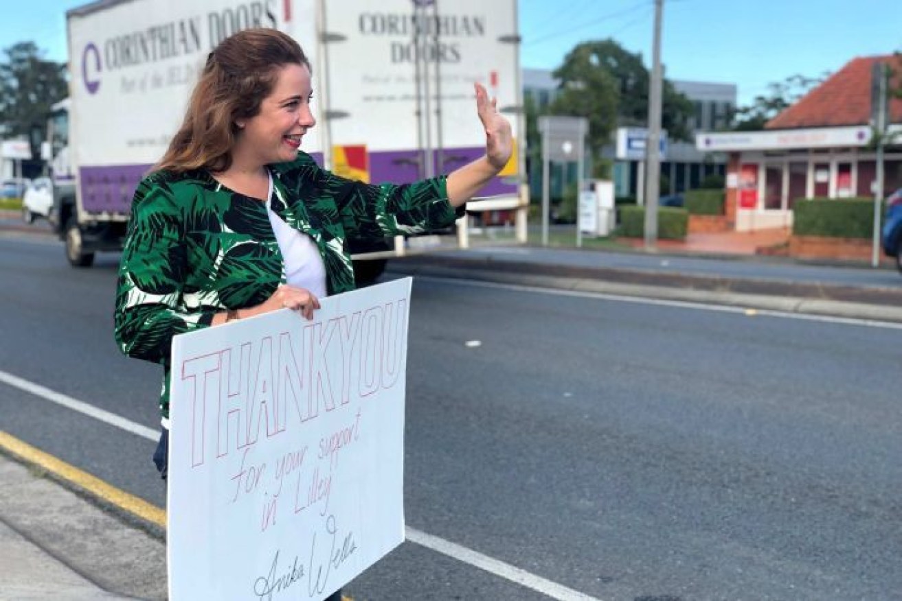 Labor's Anika Wells waves to drivers after narrowly holding onto the Brisbane seat of Lilley.