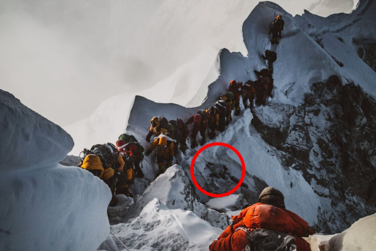 The haunting image taken by a Canadian adventure filmmaker shows a queue of Everest climbers traversing around a dead body.