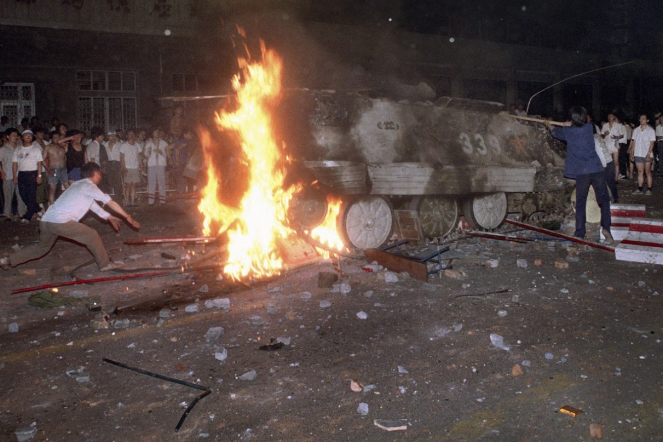 A protester places barricades in the path of a burning army tank that rammed students in Tiananmen Square on June 4, 1989.