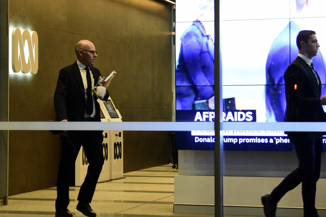 ABC editor John Lyons follows an AFP officer out of the building.