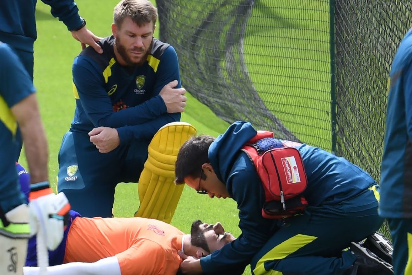 David Warner looks on as an injured net bowler receives medical attention during a training session at The Oval in London.

