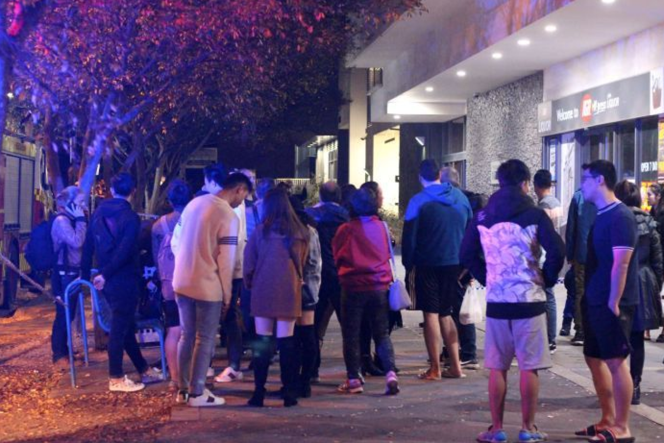 Stunned residents gather in the winter's night outside their evacuated apartment complex in Mascot.