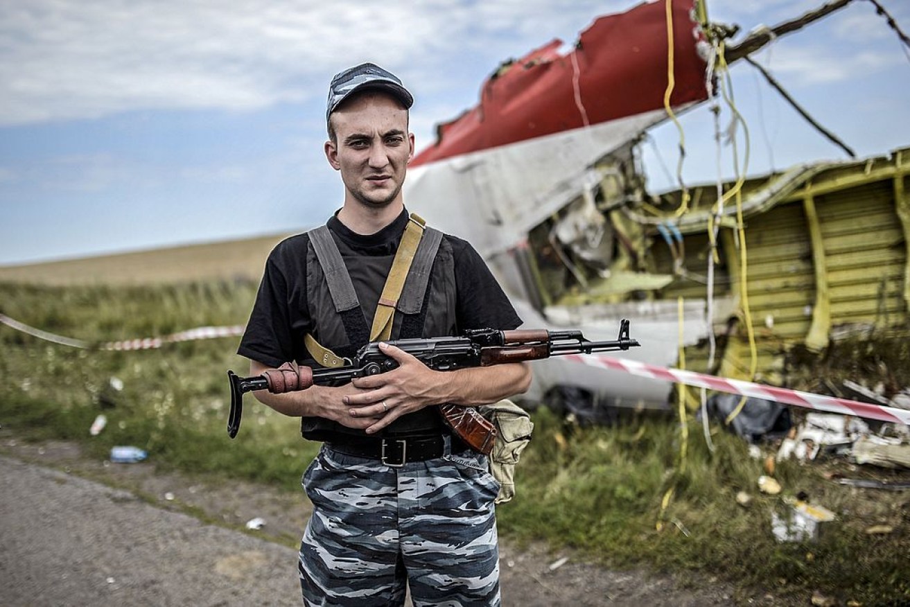 An armed pro-Russian separatist standing guard near a piece of the wreckage of the Malaysia Airlines Flight MH17 after it was shot down on July 17, 2014.