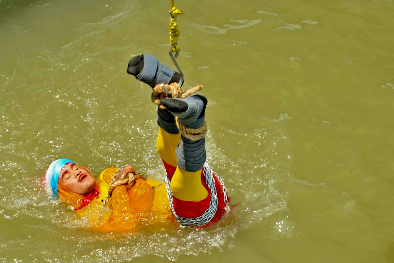 Chanchai Lahiri is lowered into a Kolkata river, bound by steel chains and ropes.