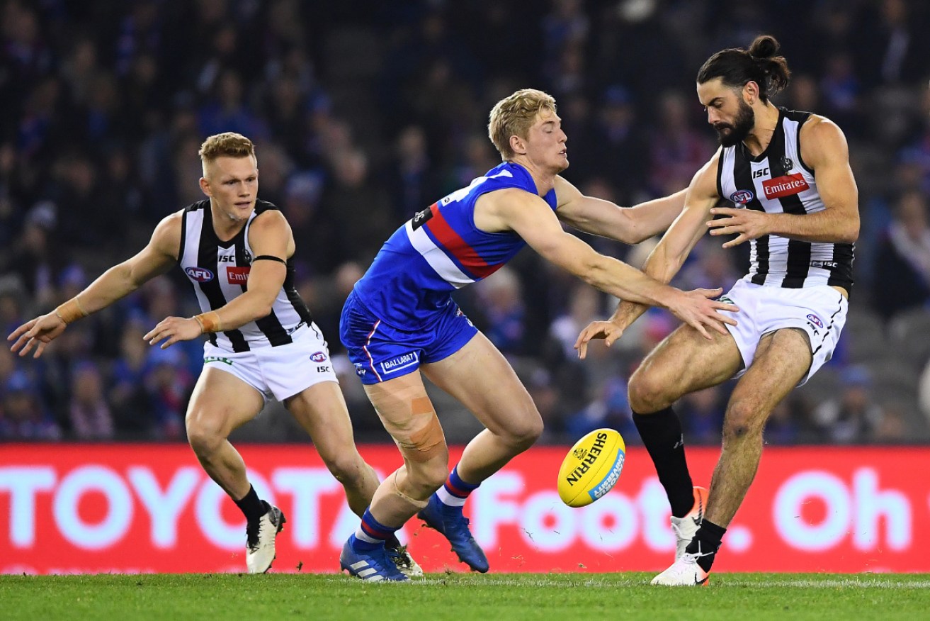 Magpie Brodie Grundy gets his kick away despite attention from Bulldog Timothy English.