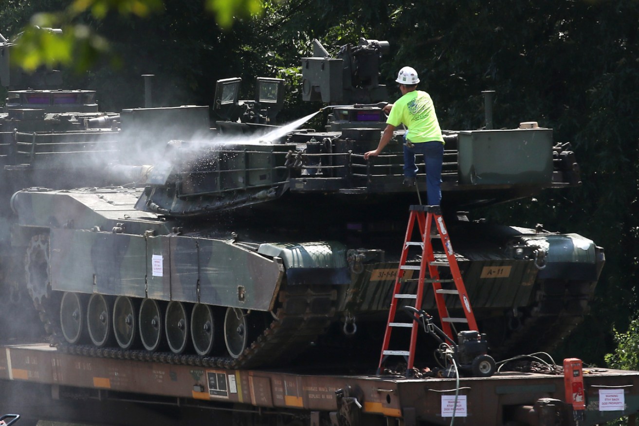 A worker washes an Abrams tank in a rail yard in Washington ahead of Thursday's Independence Day parade.