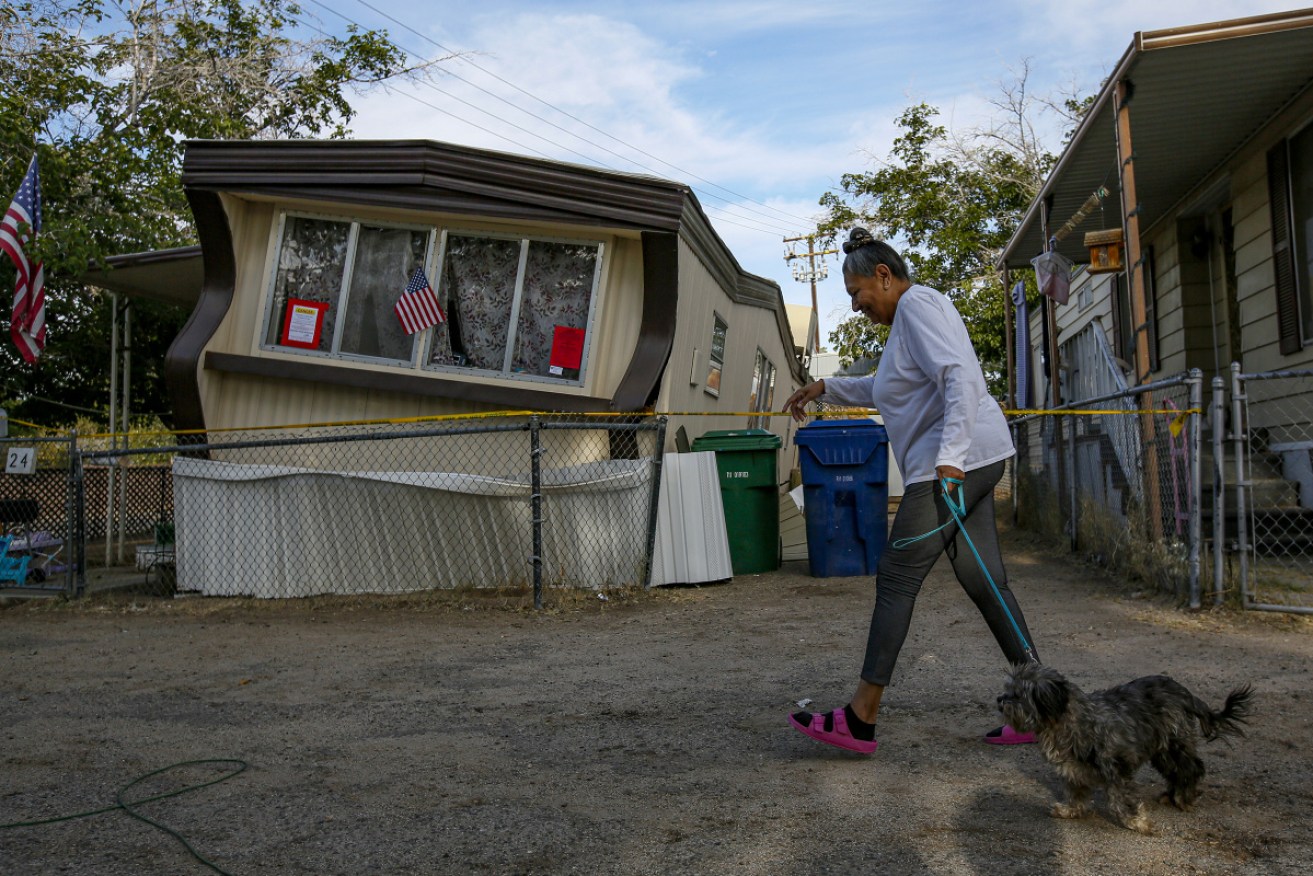Carmen Rivera, 65, on morning walk with her dog Ash passes by a mobile home dislodged in Ridgecrest.