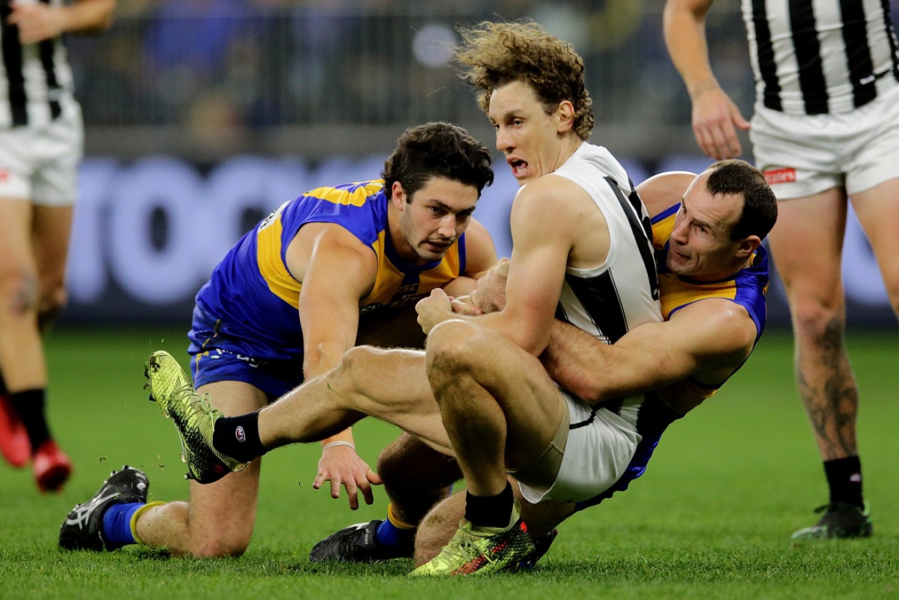 Collingwood's Chris Mayne ends up in an Eagle sandwich at Optus Stadium. 