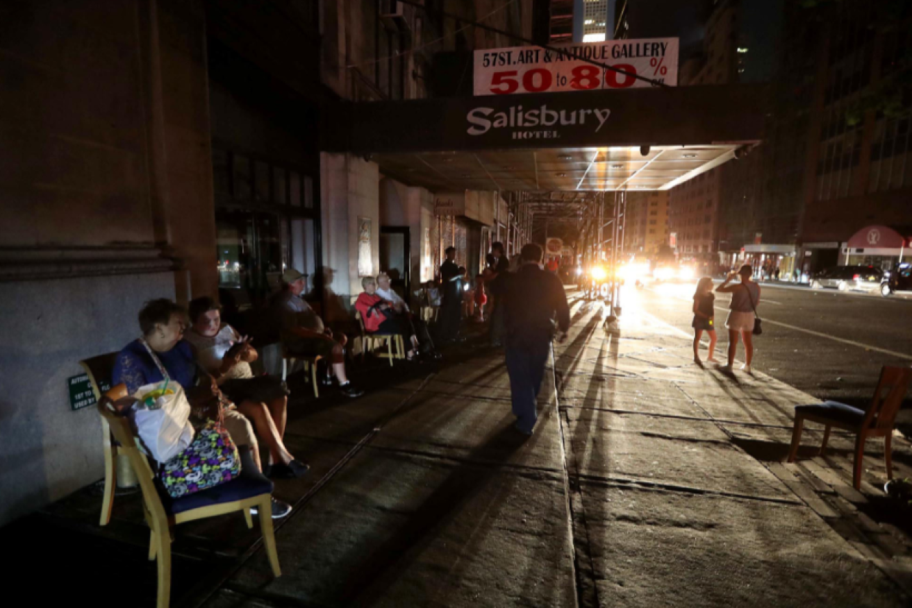 Hotel guests sit out the power age outage on the sidewalk as they wait for the lights to come on and elevators to start working. 