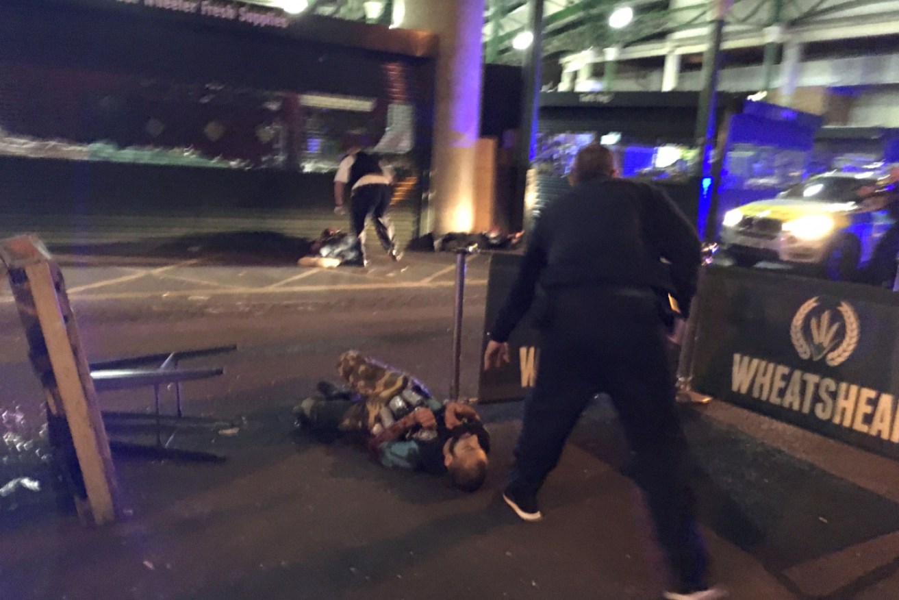 One of the attackers is tackled by a police officer.