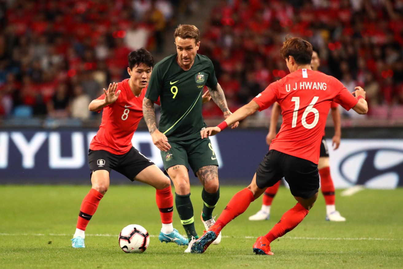 Socceroos striker Adam Taggart shields the ball from South Korea's Ju Sejong and Hwang Uijo at Busan in June.