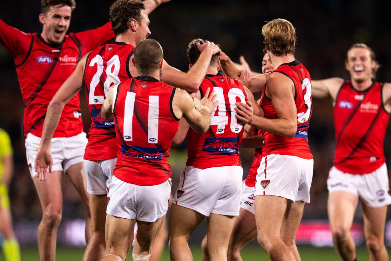 Essendon players celebrate their stirring win on the road against the Crows. 