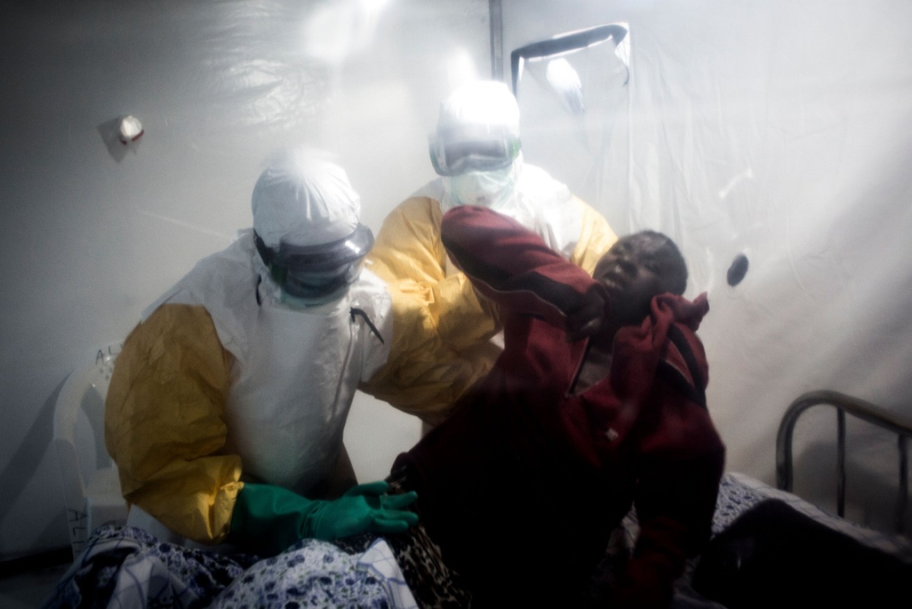 An Ebola patient is lifted up by two medical workers in Beni. 
