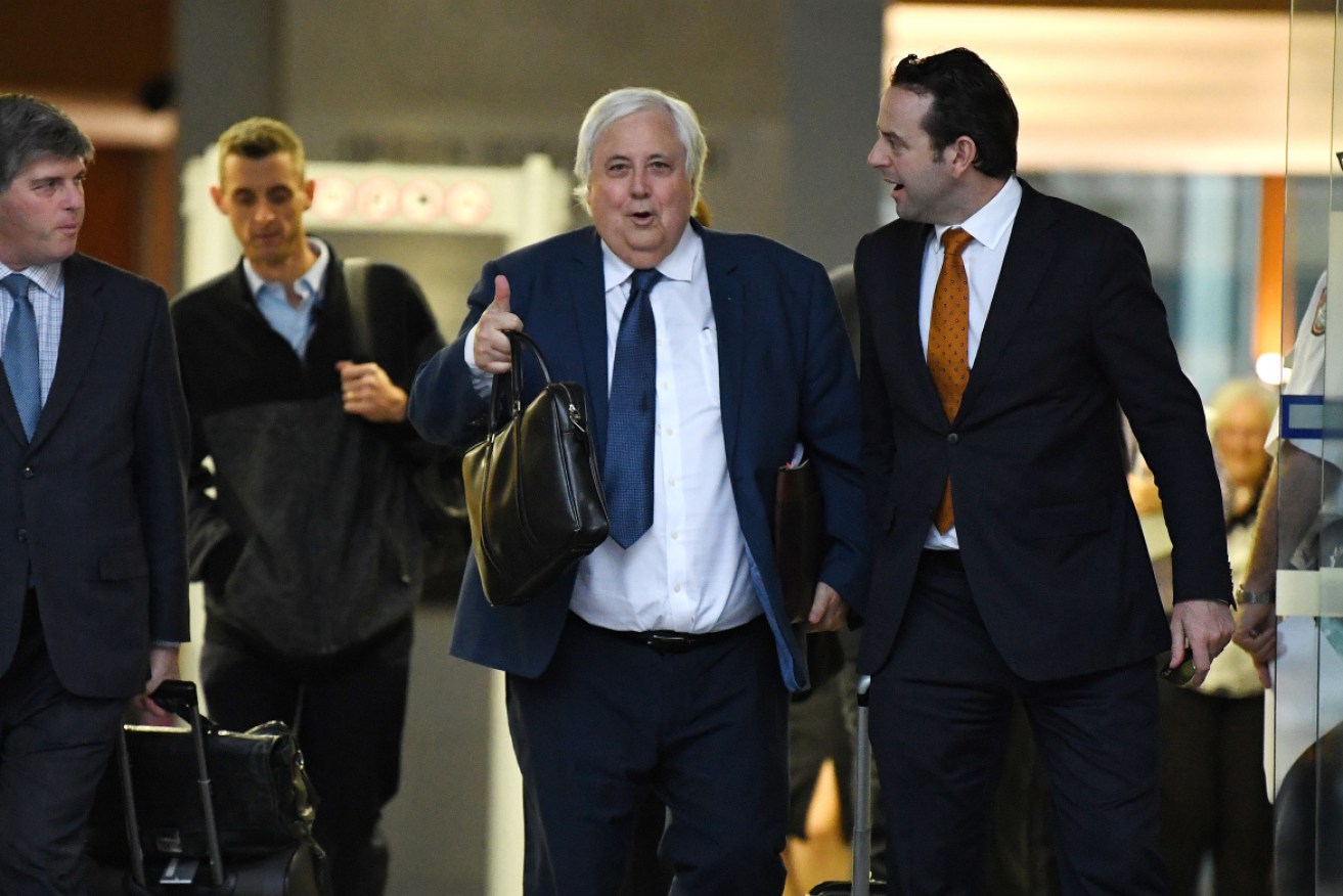 Clive Palmer (centre) leaves court with his lawyers after an earlier hearing.