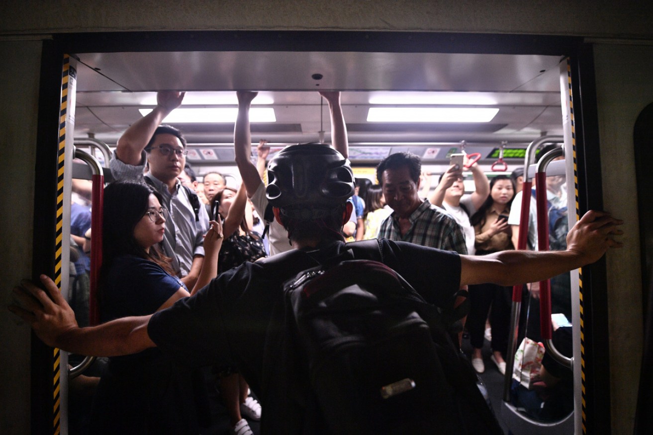 A protester holds up a commuter train by blocking its doors open on Monday morning.