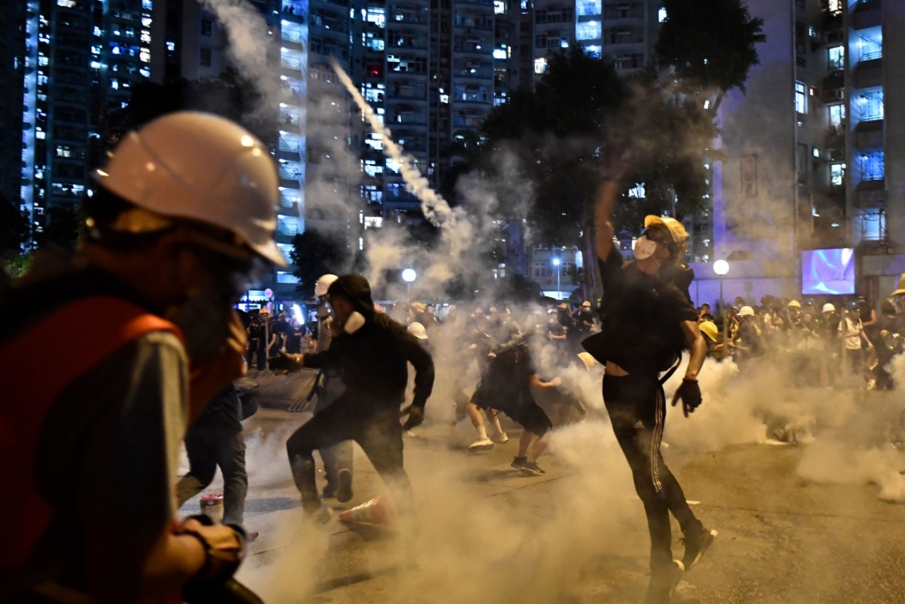 Protesters throw tear gas back at riot police during a clash in Hong Kong on Monday.
