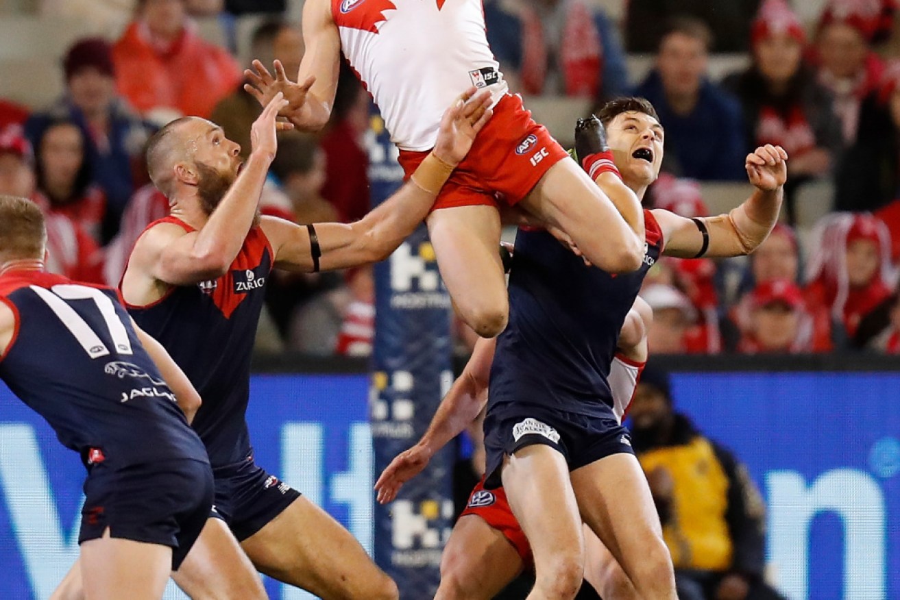 Isaac Heeney of the Swans attempts a spectacular mark over Melbourne's Jake Lever.