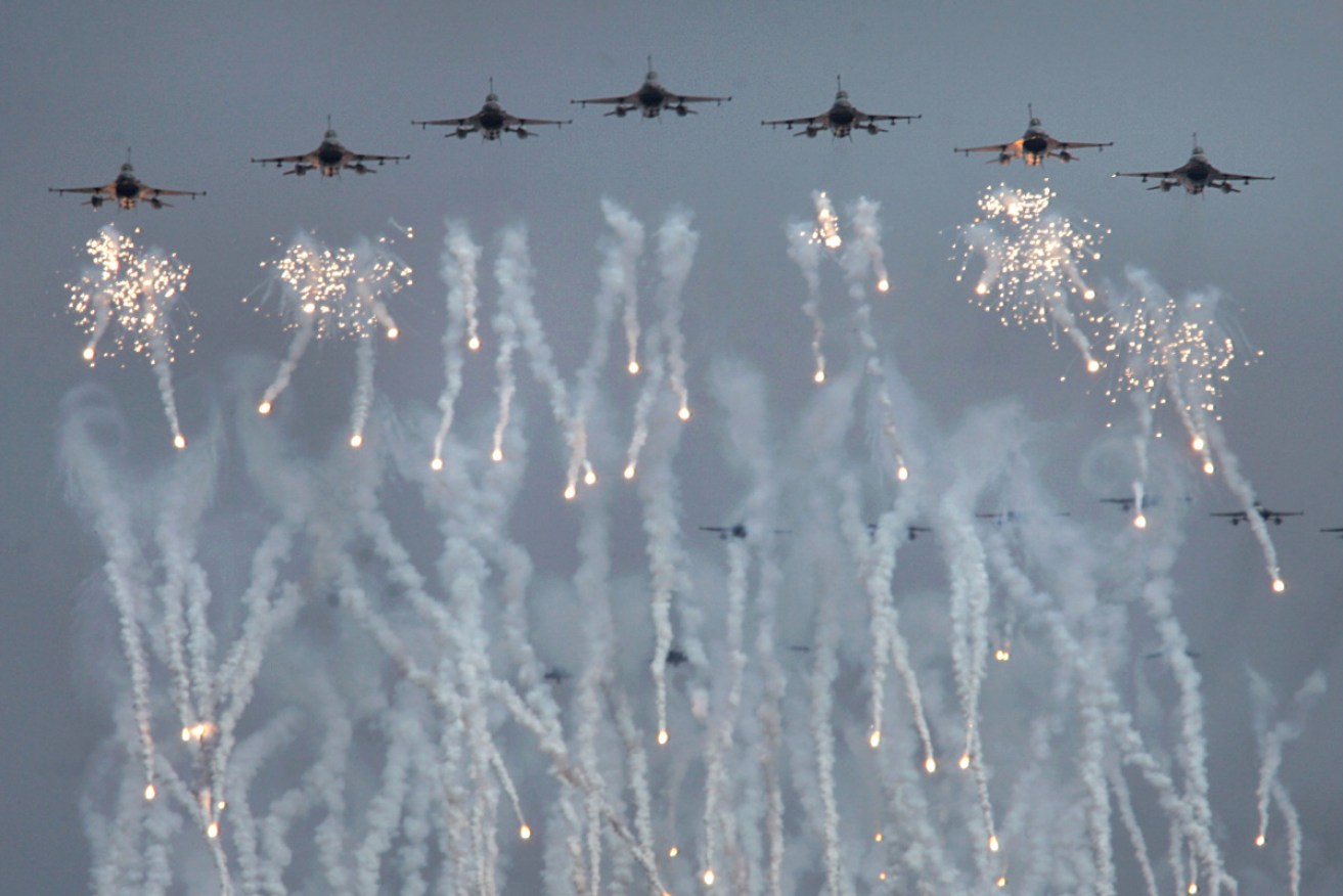 Taiwanese Air Force F-16 fighter jets fly in formation as they drop anti-missile decoys . <i>Photo: AAP</i>