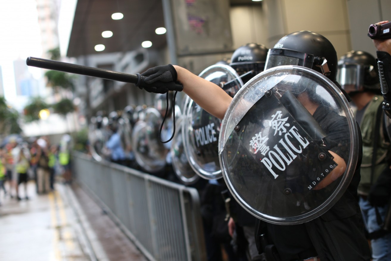 Riot police stand guard as anti-government protesters gather outside the Mong Kok Police station.