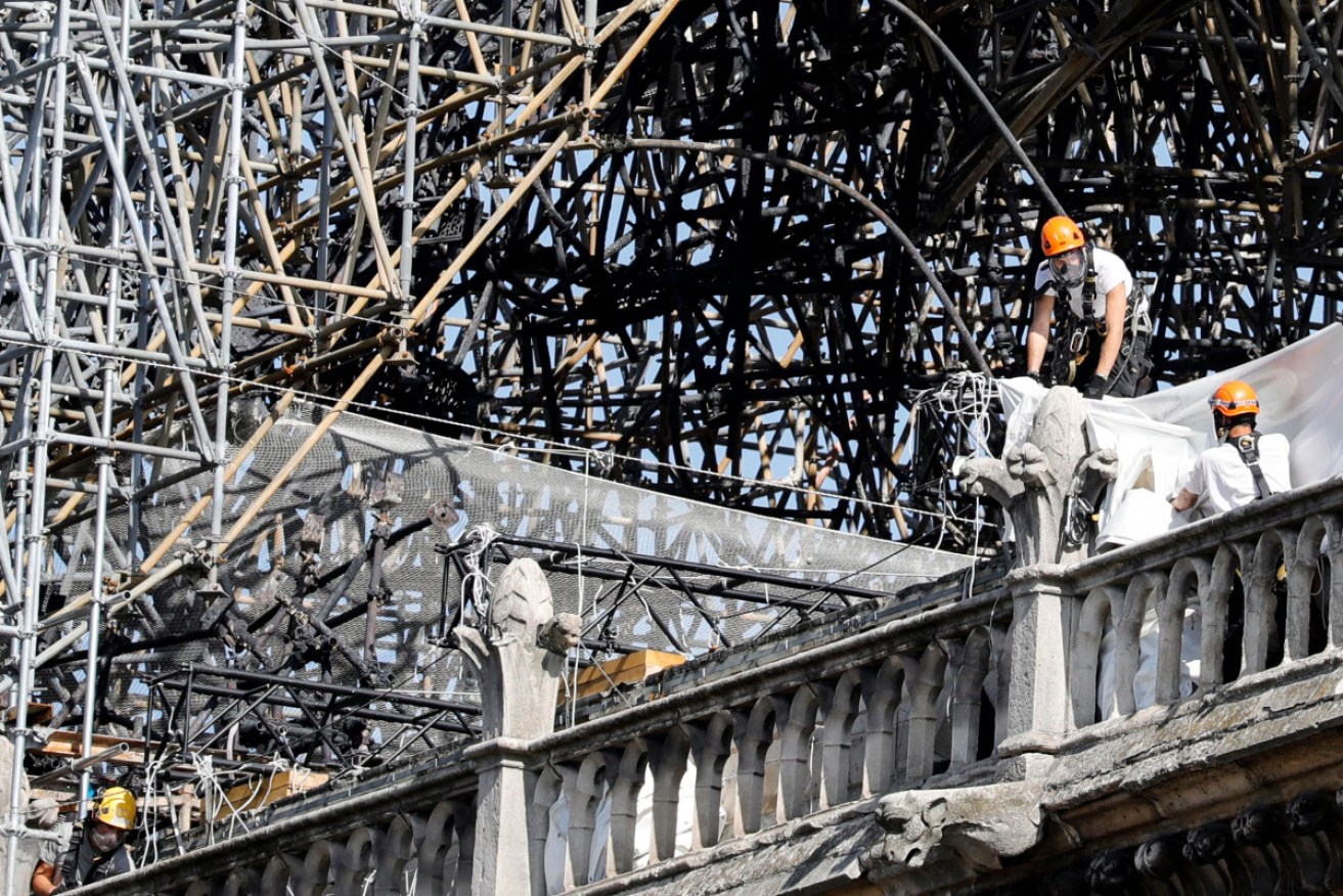 Workers wear masks as they survey the damaged area of the Notre Dame cathedral after the restart of consolidation works.